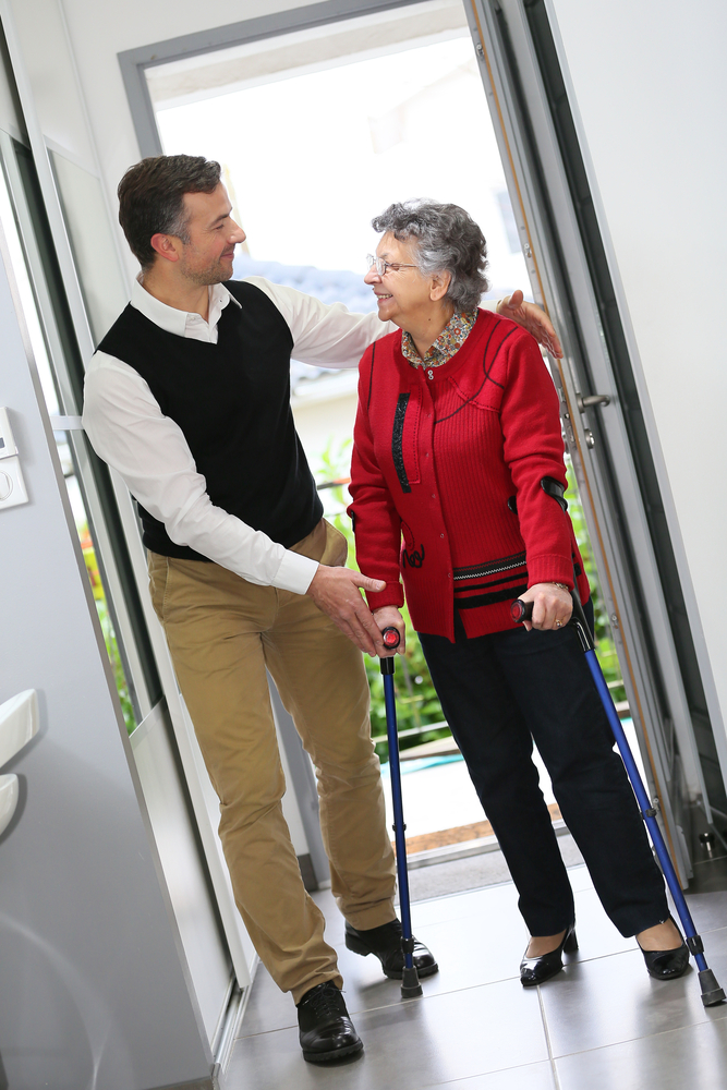 Man helping elderly woman with crutches Man helping elderly woman with crutches