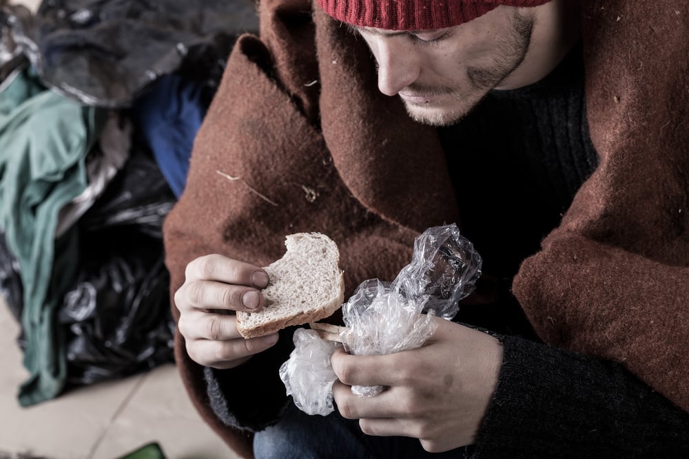 Poor man eating sandwich on the street